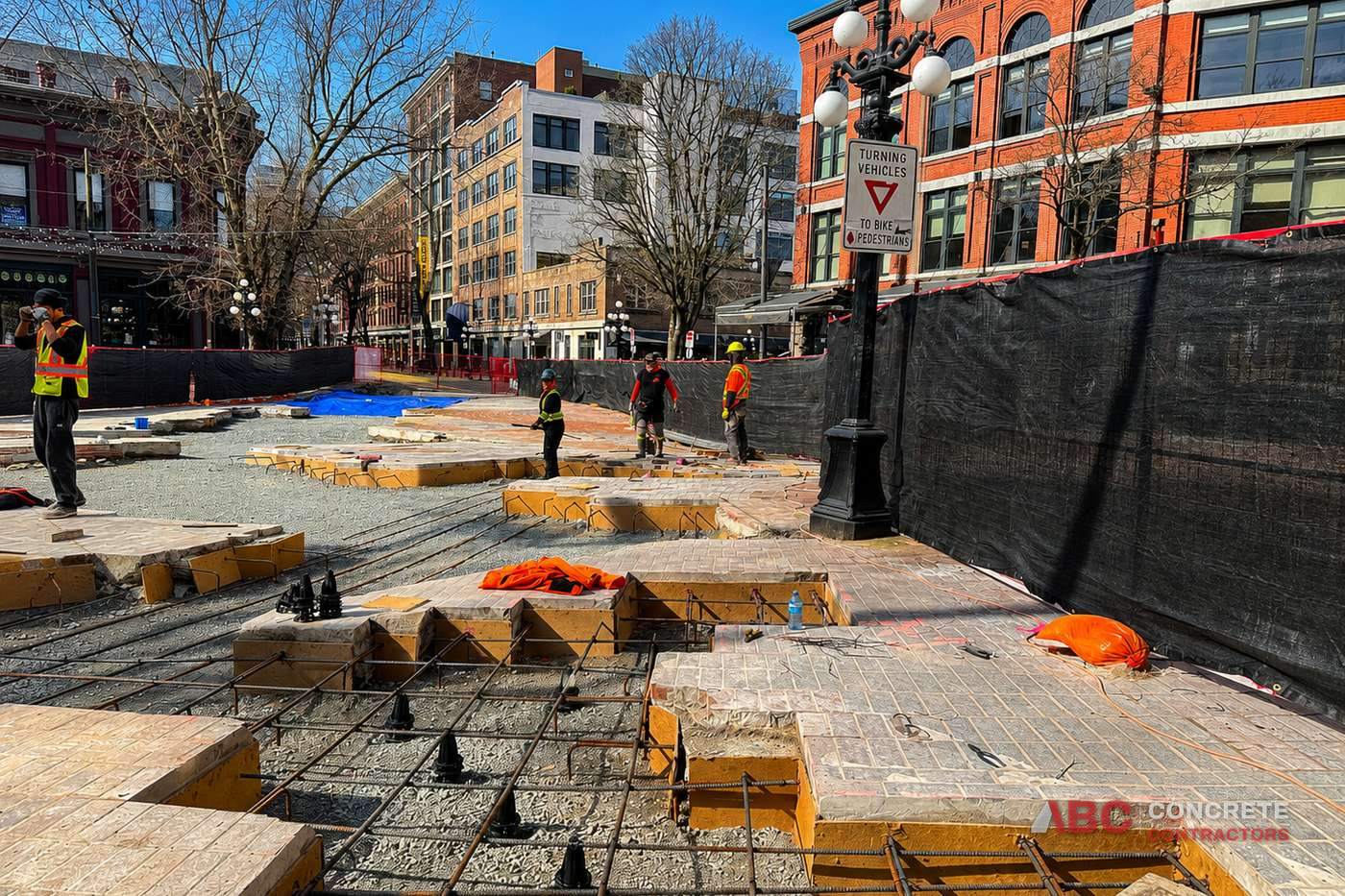 ABC Concrete crew forming and tying rebar for a commercial pour on a Gastown street in Vancouver, with heritage brick buildings behind